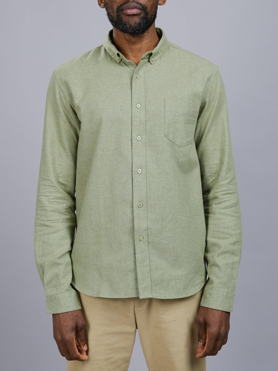 Dressed in a light green Max Brushed Flannel Shirt by ID Menswear, 100% cotton with long sleeves and a left pocket, paired with beige pants. Background is plain gray; persons head partially visible.