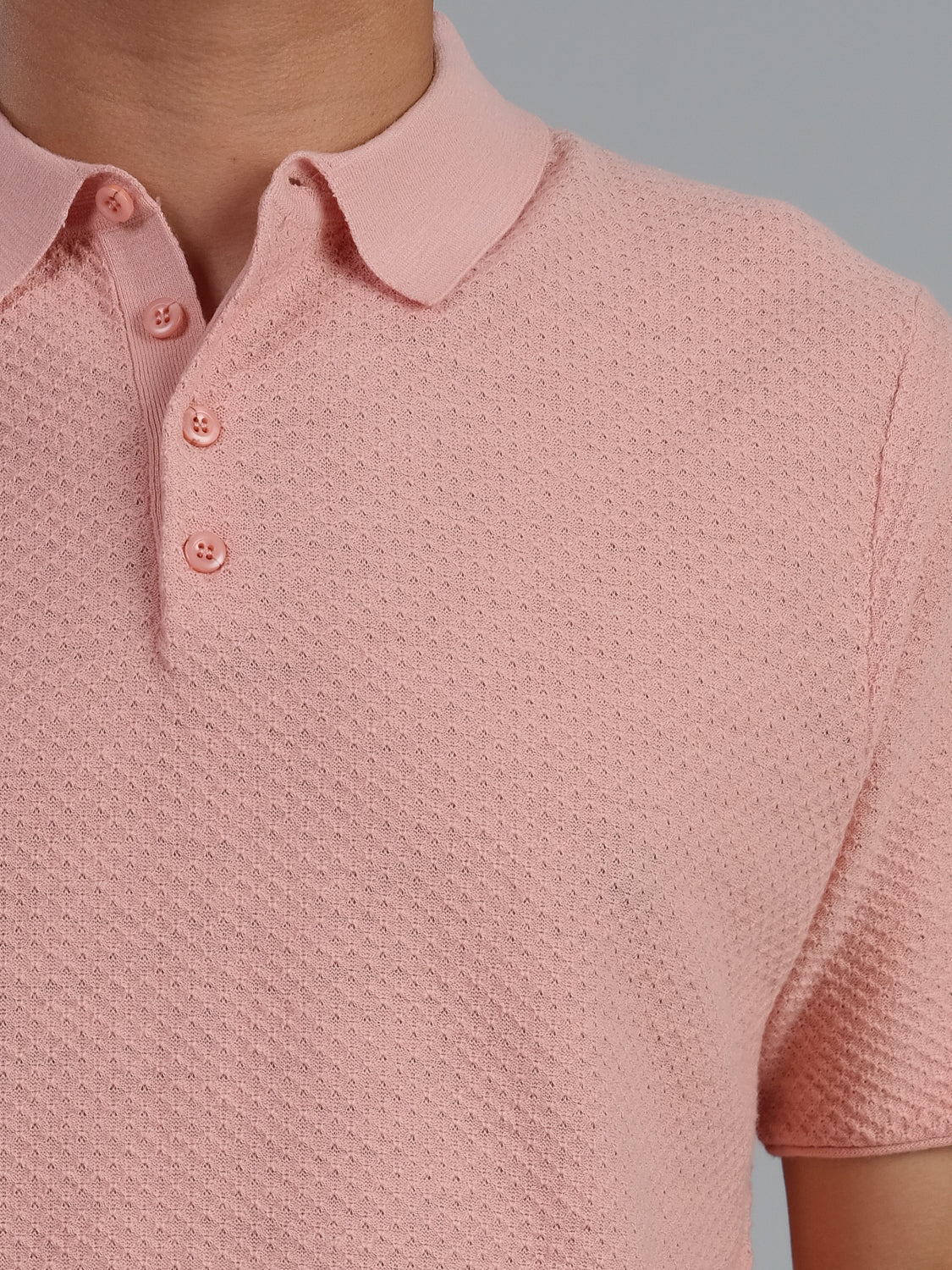 A close-up features the Phoenix Super Fine Cotton Knit Polo by ID Menswear—a stylish, textured pink shirt with a buttoned collar against a plain gray background, showcasing its subtle dotted pattern.