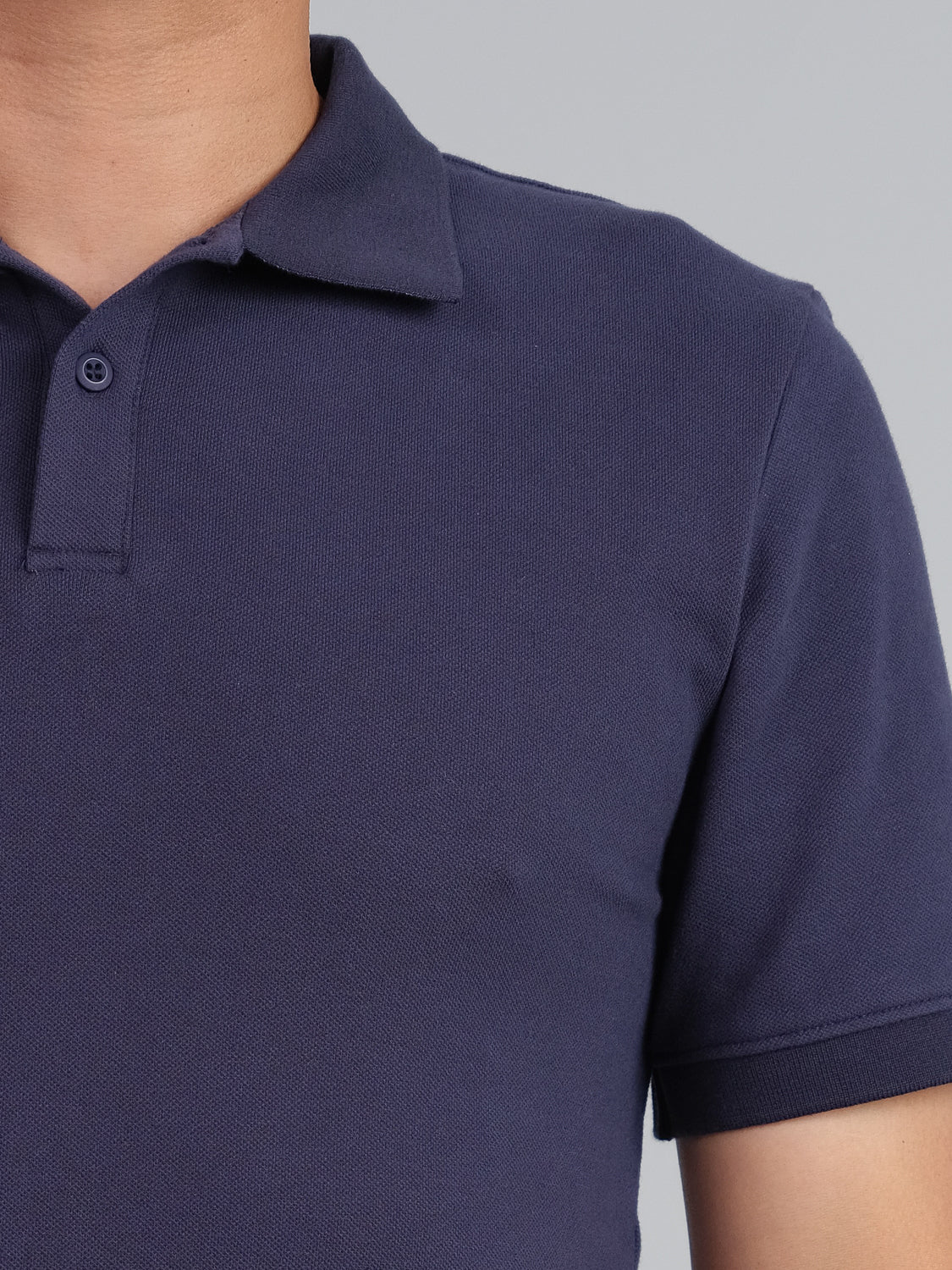 A close-up highlights the classic style of ID Menswears Ranger Classic Cotton Mesh Polo in dark blue, featuring its textured lightweight cotton fabric and a visible button on a short sleeve. The persons face is not shown.