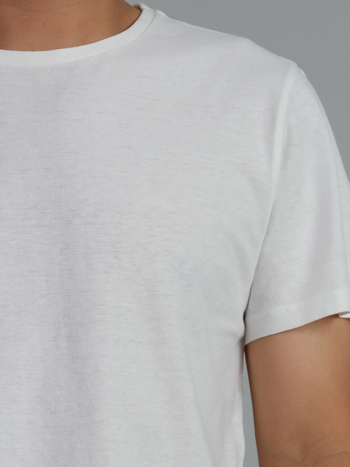 A close-up of a person wearing the Dope Hemp Organic Cotton Tee from ID Menswear shows the upper part and shoulder against a neutral gray background, highlighting its soft, sustainable hemp cotton blend.