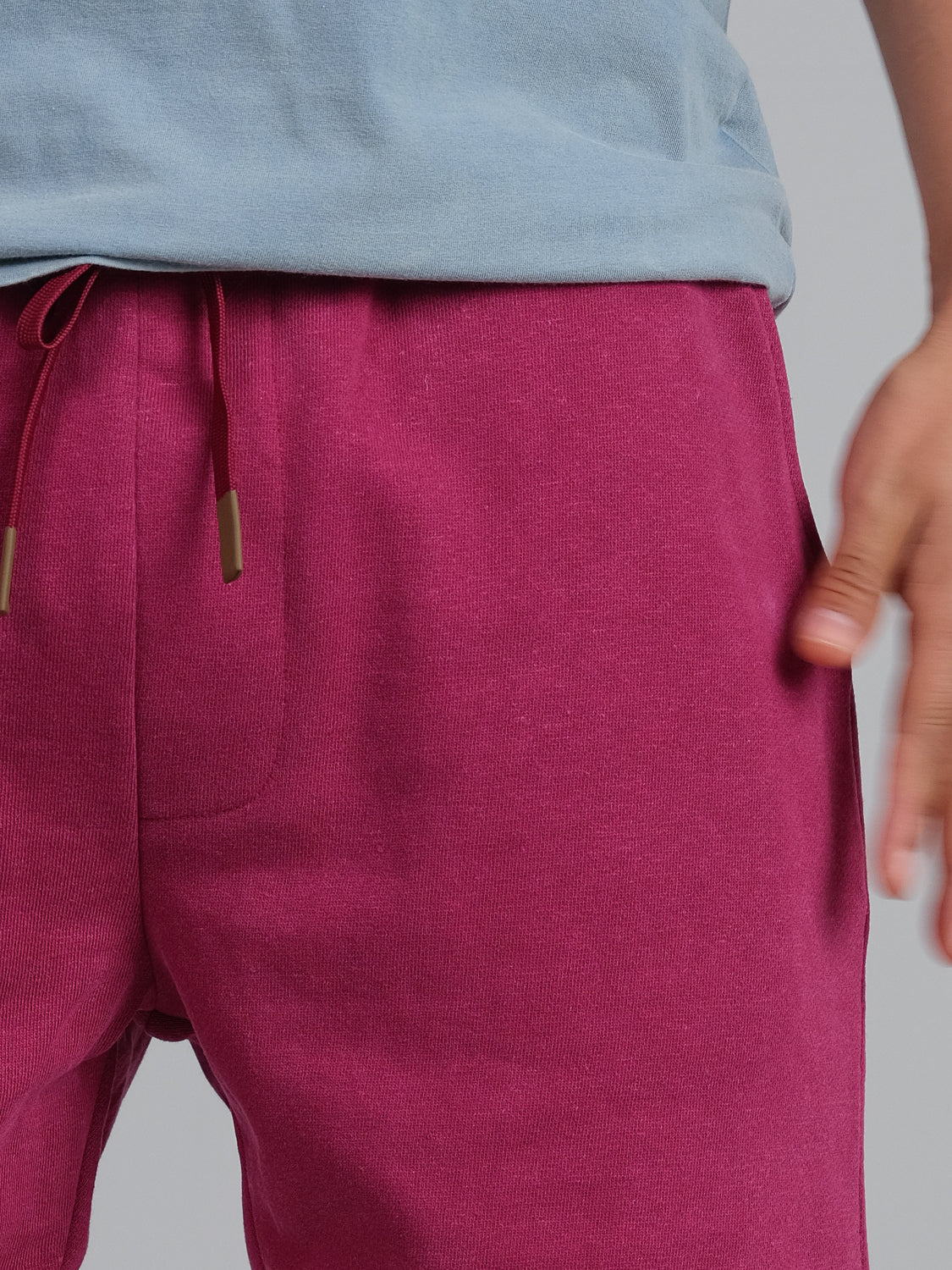 A person is wearing a light blue shirt and ID Menswears vibrant pink Walker Hemp Cotton Terry Short, with one hand in the pocket and a drawstring visible at the waistband.