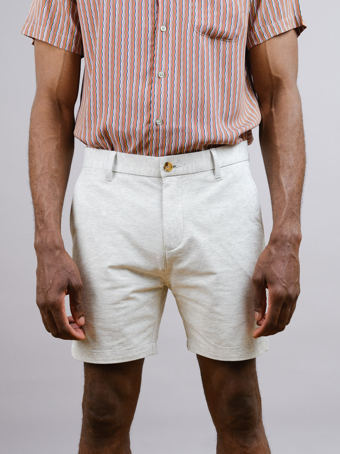 A person stands against a plain background, wearing a short-sleeve patterned shirt tucked into ID Menswears Eckford 5 Inseam Stretch Short, cropped from shoulders down to showcase its relaxed fit and all-day comfort style.