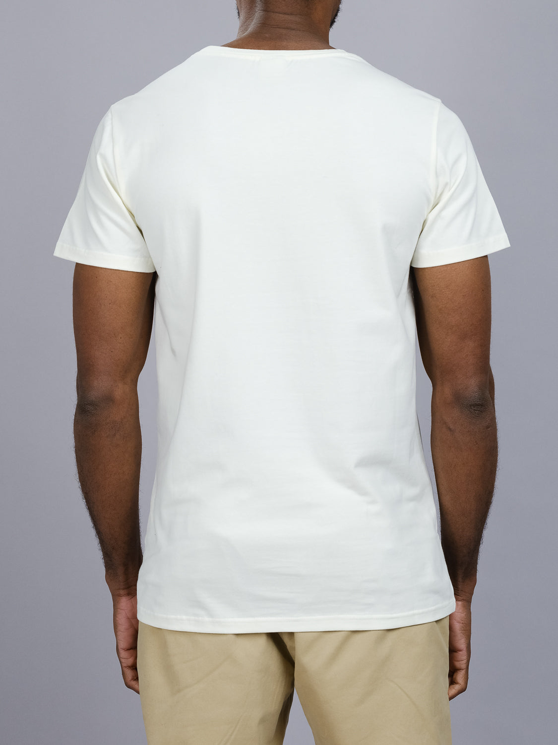 A person is shown from the back, wearing a form-fitting plain white Form Crew Neck Tee by ID Menswear and beige pants, against a gray background.