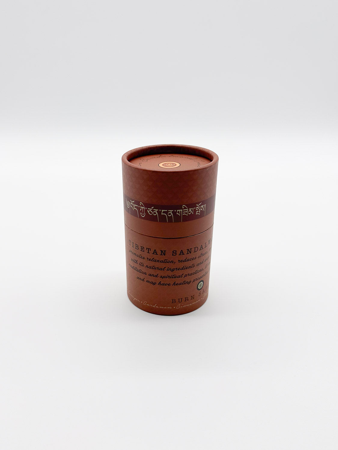A reddish-brown cylindrical container labeled Tibetan Sandalwood Incense by ID Menswear, ideal for relaxation, features text in English and possibly Tibetan, set against a plain white background.