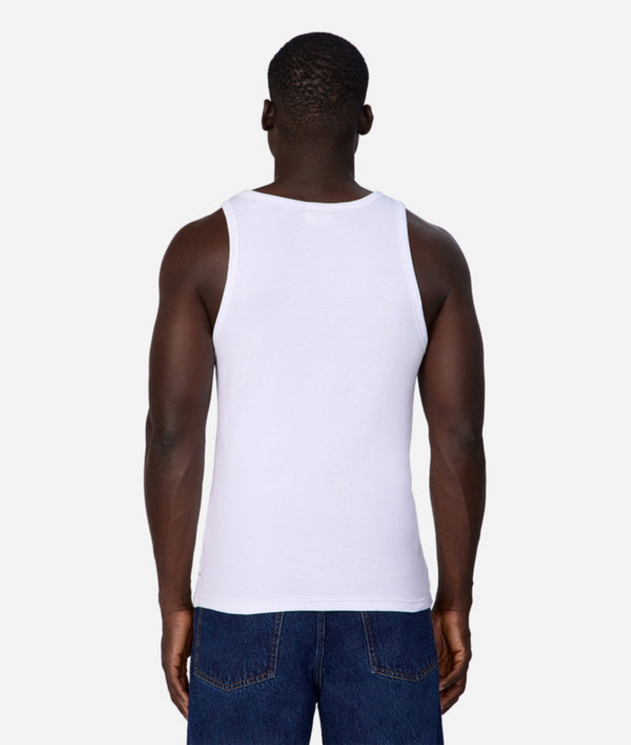 A man faces away from the camera, highlighting the Industrie Washed Brando Ribbed Tank Top and blue jeans—summer staples—set against a plain white background.