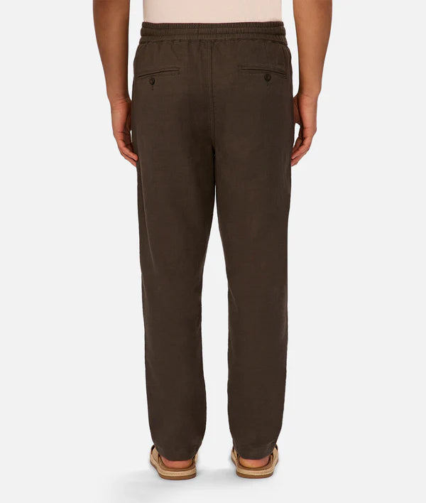 Back view of a man wearing Industrie’s The Mallorca Pant in brown linen-cotton blend with a drawstring waist and tan sandals, set against a white background.