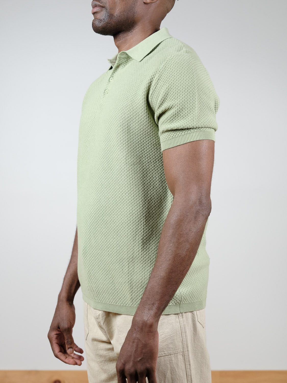 A man in the ID Menswear Tucson Knitted Cotton Polo in light green and beige pants stands sideways against a plain background.
