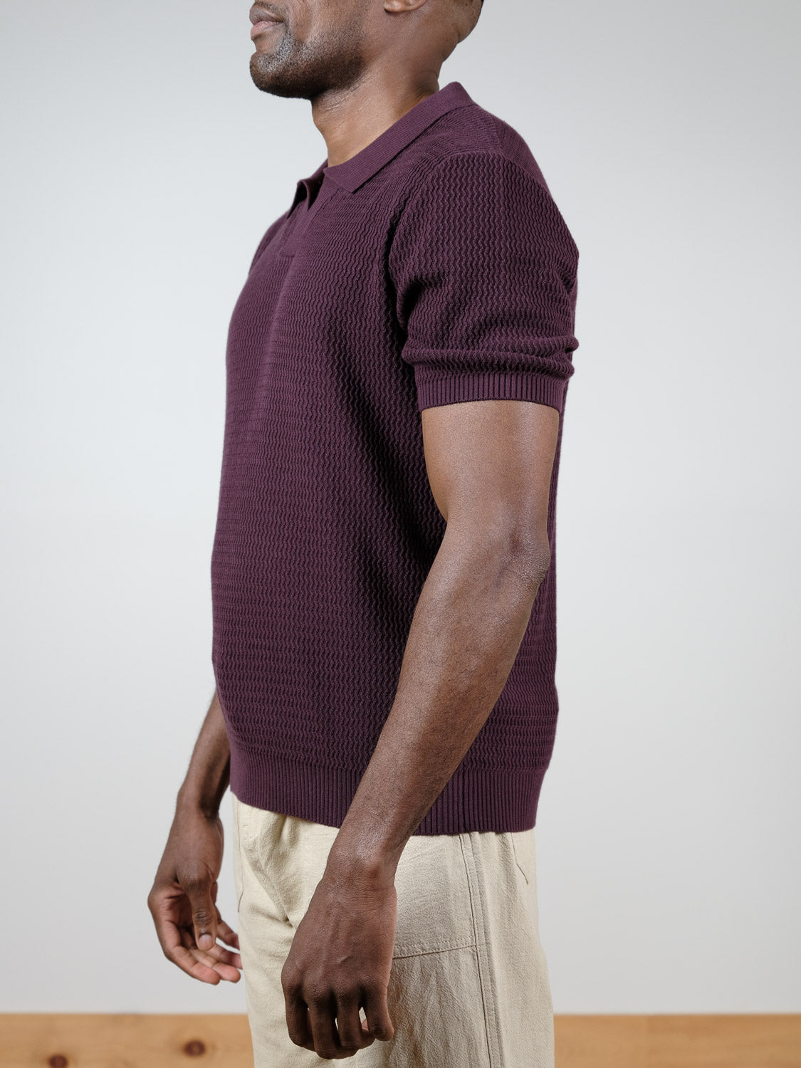 A man stands in profile against a plain light background, wearing the Mecca Knitted Cotton Polo from ID Menswear paired with light beige pants.