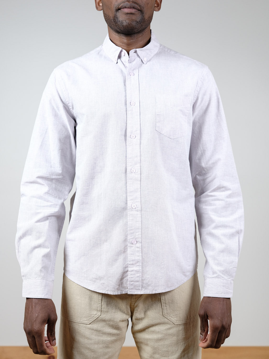 A man faces forward against a plain background, wearing the ID Menswear Darwin Long Sleeve Shirt—relaxed fit with a chest pocket—paired with light beige pants.