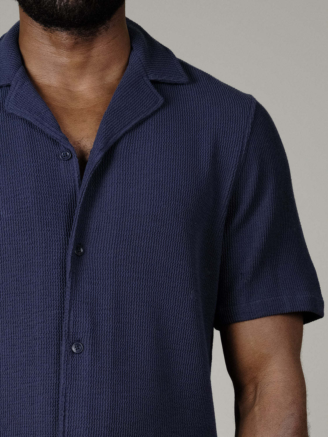 A man wears the Casual Friday Archer SS RC Knitted Shirt—a short-sleeved, navy resort-collar button-up with a textured finish—shown from shoulders to mid-torso against a plain background.