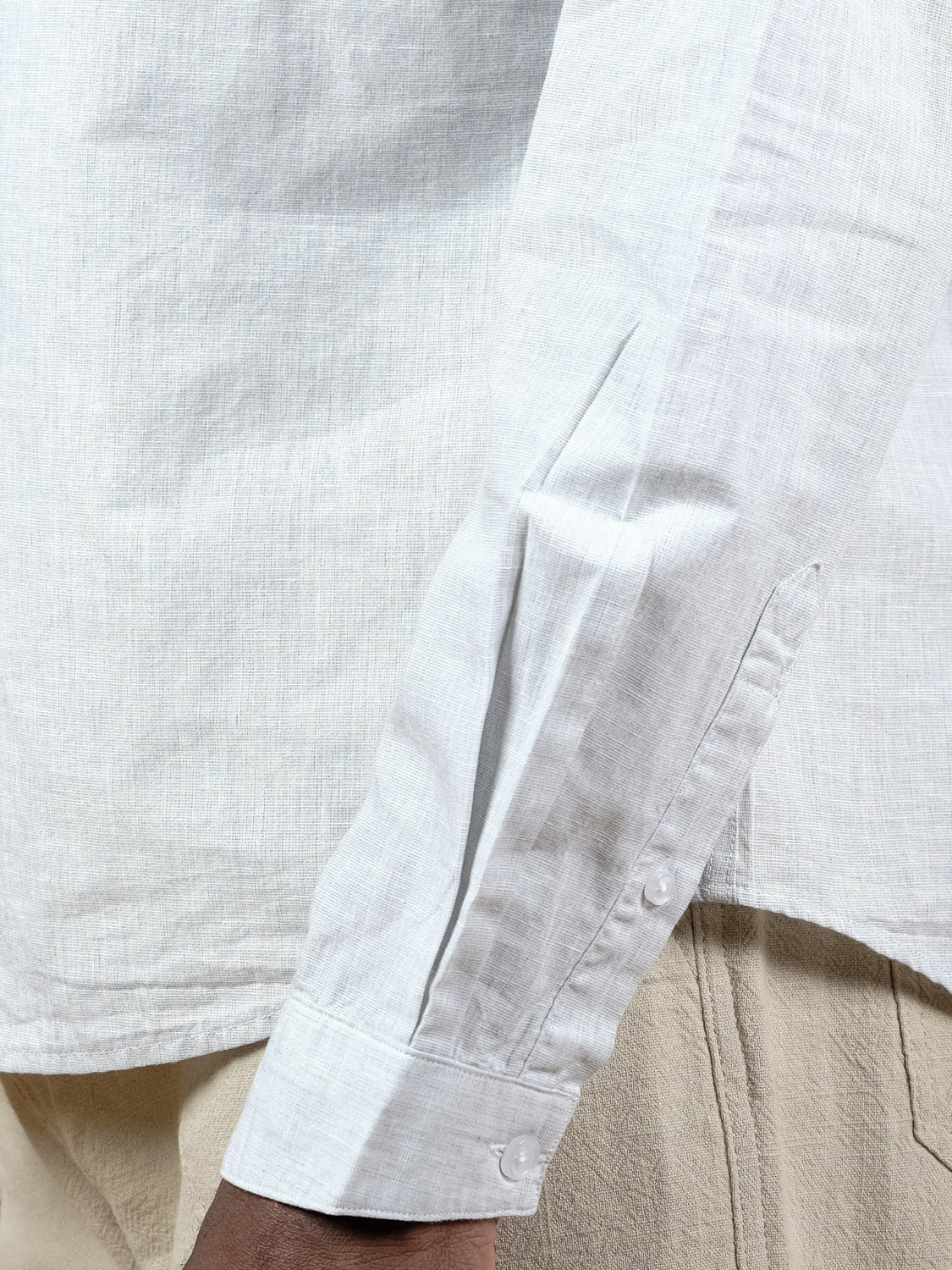 A close-up of a person wearing the Darwin Long Sleeve Shirt by ID Menswear, featuring a relaxed fit and lightweight cotton. The sleeve partially covers their hand and is styled with beige pants for an effortlessly stylish look.