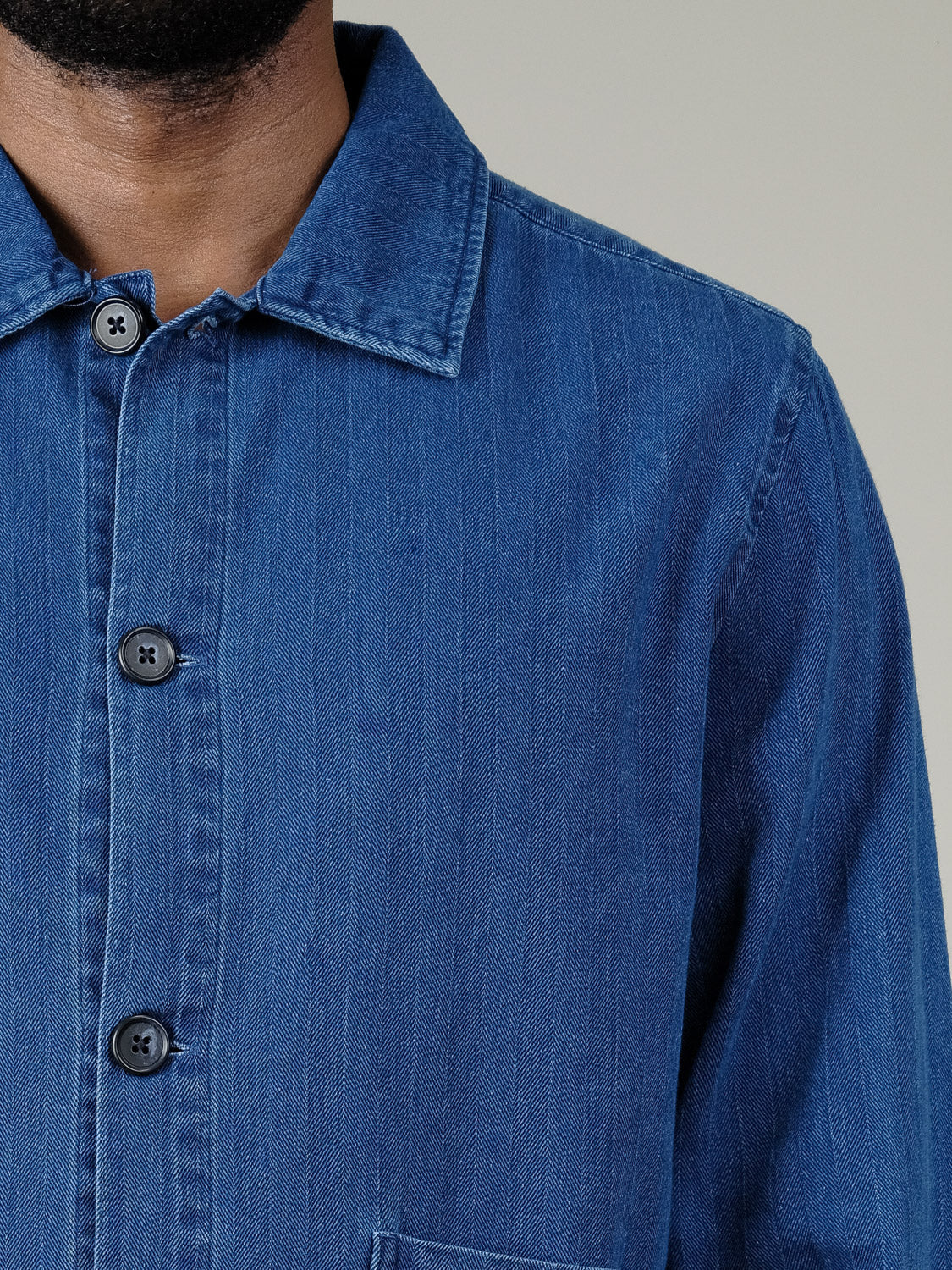 Close-up of a person wearing the Casual Friday Asplund Herringbone Jacket, featuring black buttons and a pointed collar. Only the lower face, neck, and upper body are visible.
