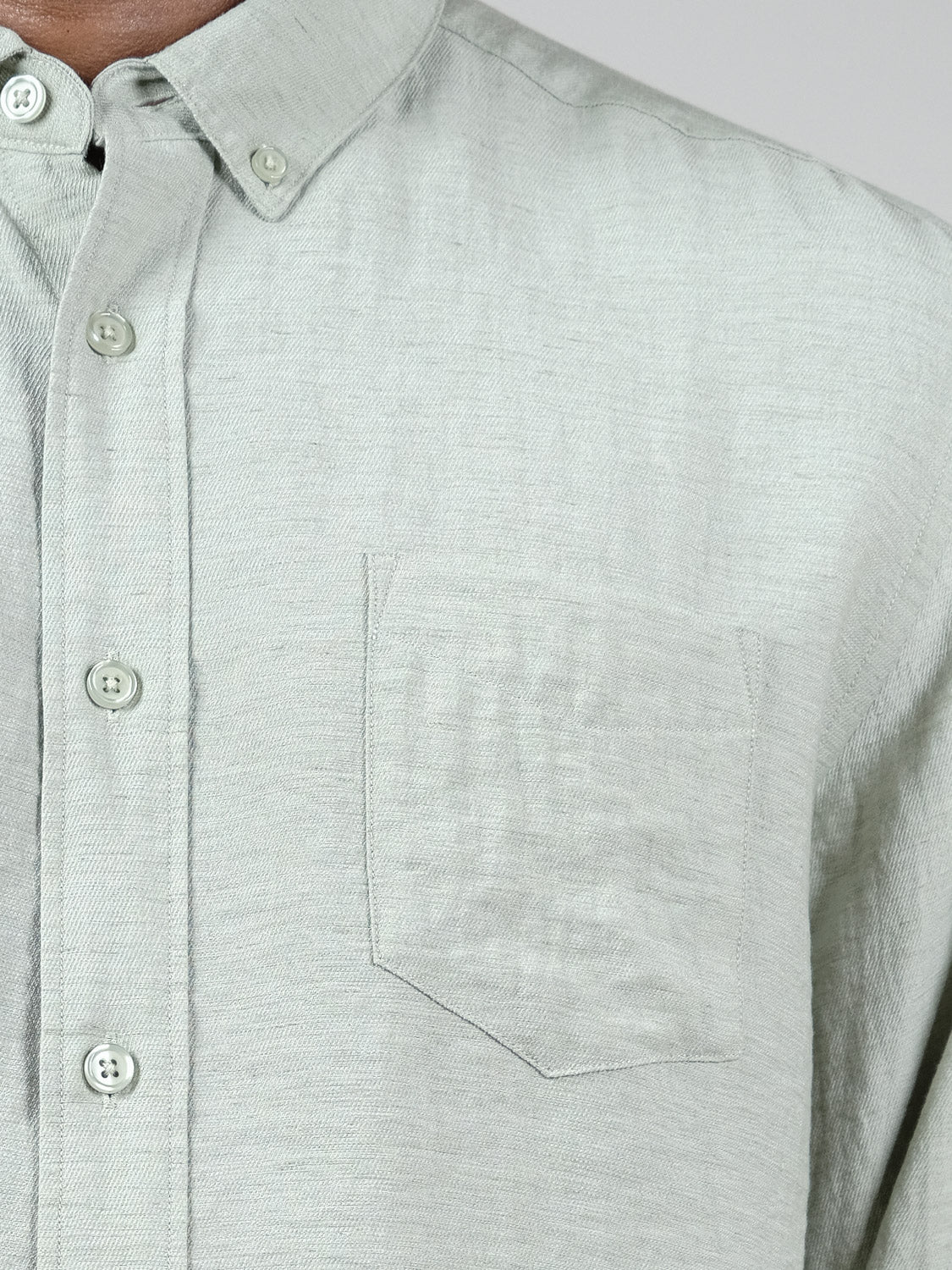 Close-up of the ID Menswear Lagos Long Sleeve Shirt in light grey, featuring a left chest pocket, subtle texture, relaxed fit, and button-down collar. This breathable linen shirt is shown being worn.