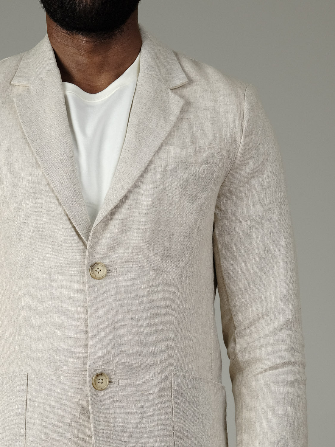 A man wears the Casual Friday Torup Linen Blazer over a white tee, shown from shoulders to waist against a plain grey background. His face is partially out of frame.