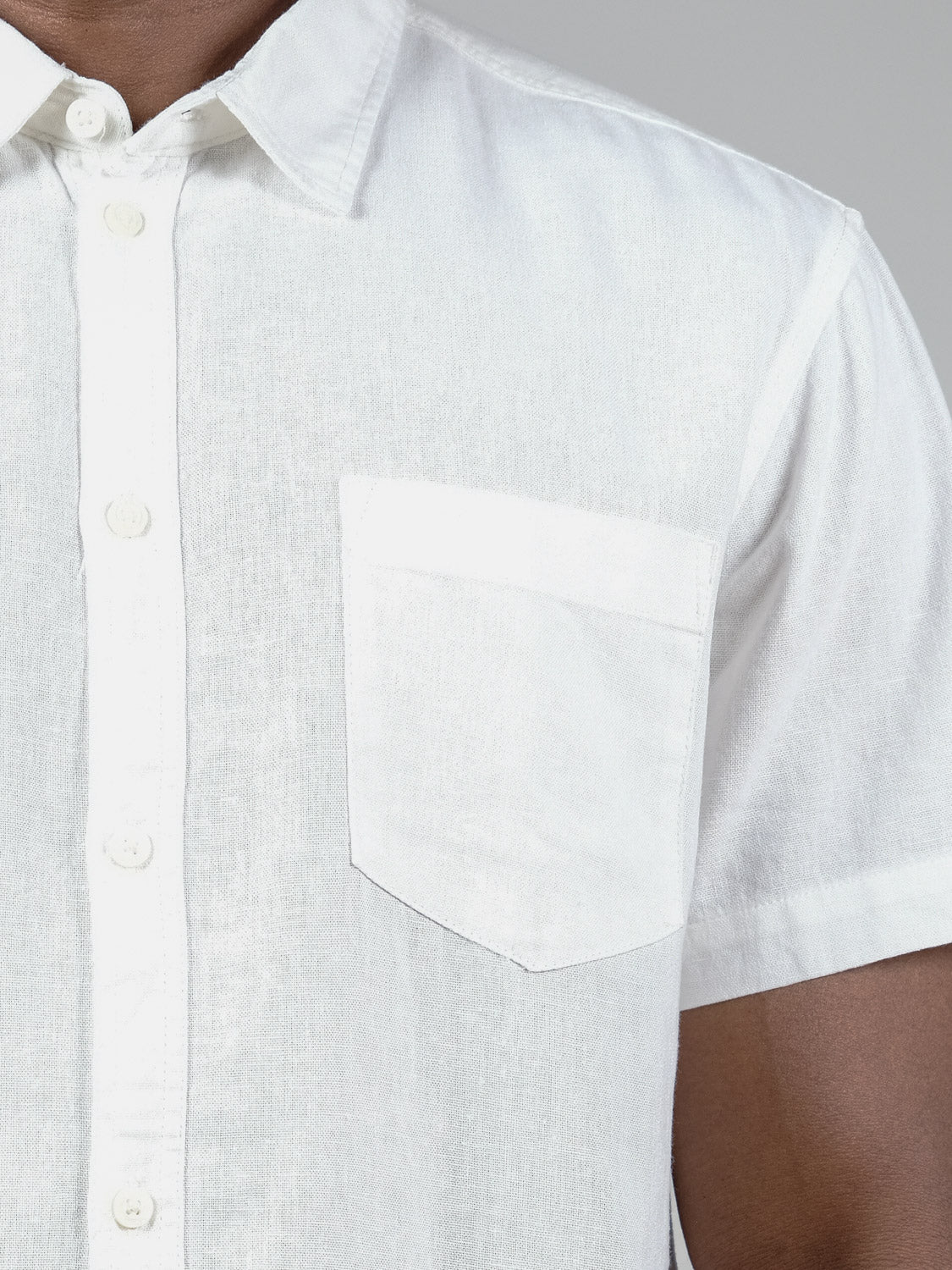 A close-up of the Allan Short Sleeve Shirt by !Solid—a white linen men’s button-up with a chest pocket—shows the left side and arm, highlighting its breathable fabric against a neutral background.