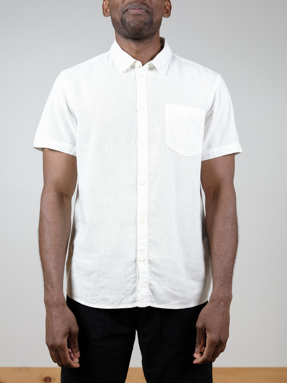 A man wears the !Solid Allan Short Sleeve Shirt with a chest pocket and black pants, standing against a plain light gray background.
