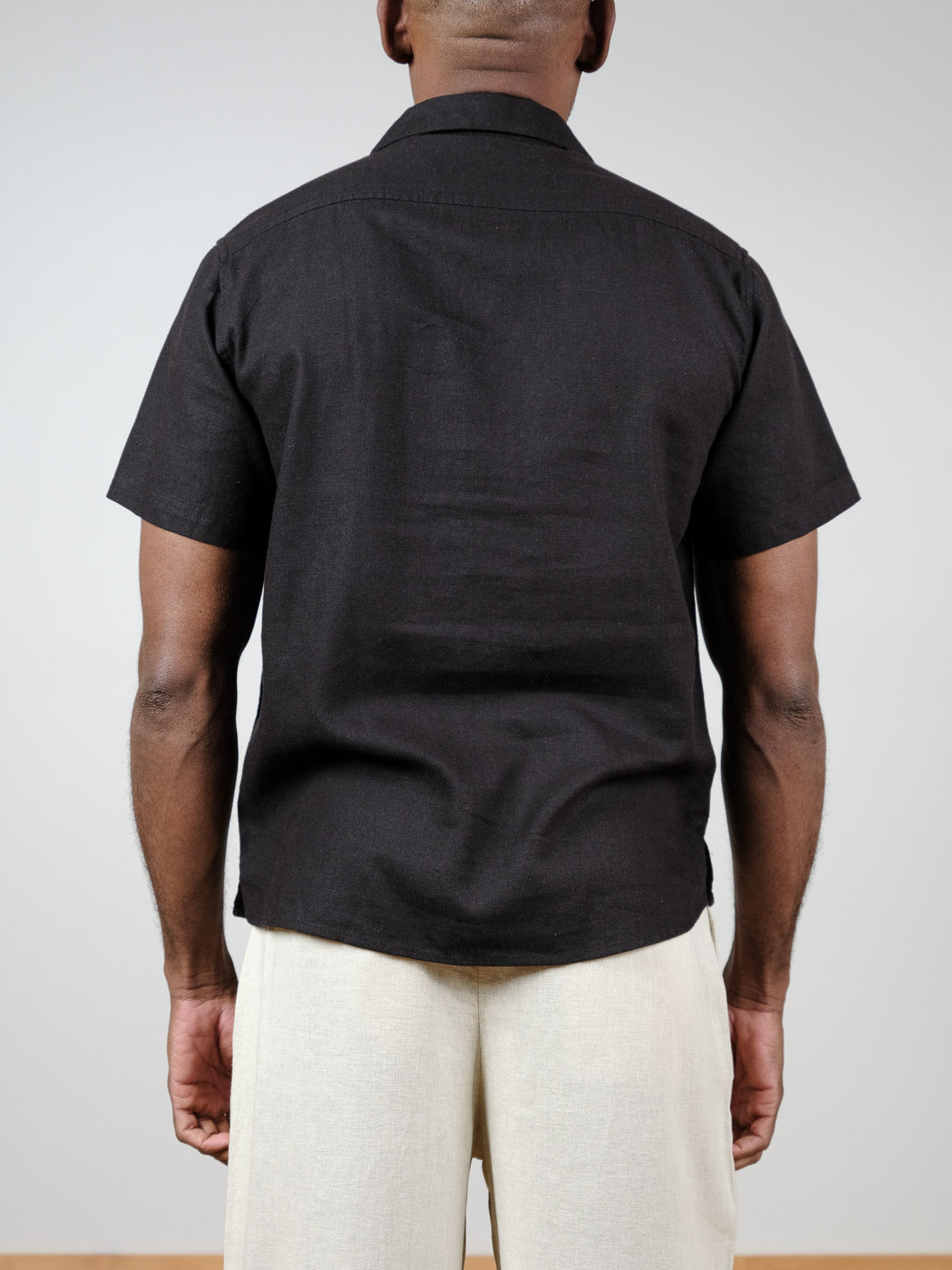 A person stands facing away from the camera, wearing the !Solid Allan Cuba Woven Short Sleeve Shirt and light-colored pants against a plain, light gray background.