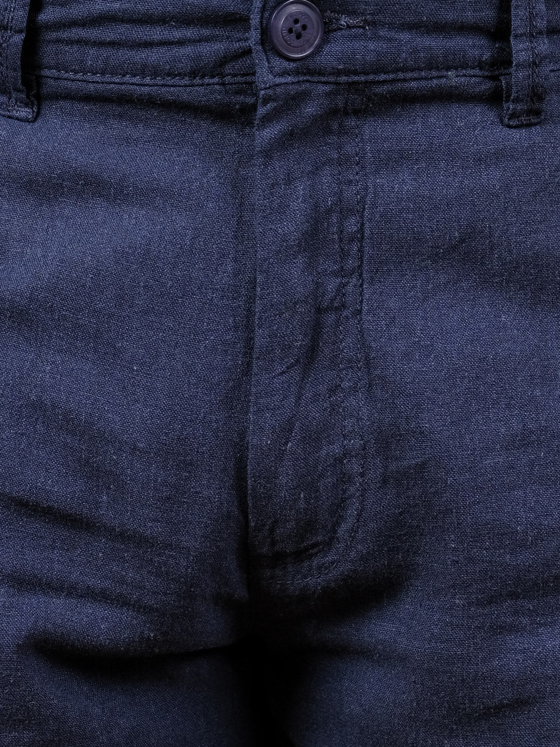 Close-up of the front of dark blue denim jeans showing the waistband, button, and fly—perfect for pairing with regular fit shorts like our !Solid Aurelius Short for a versatile look.