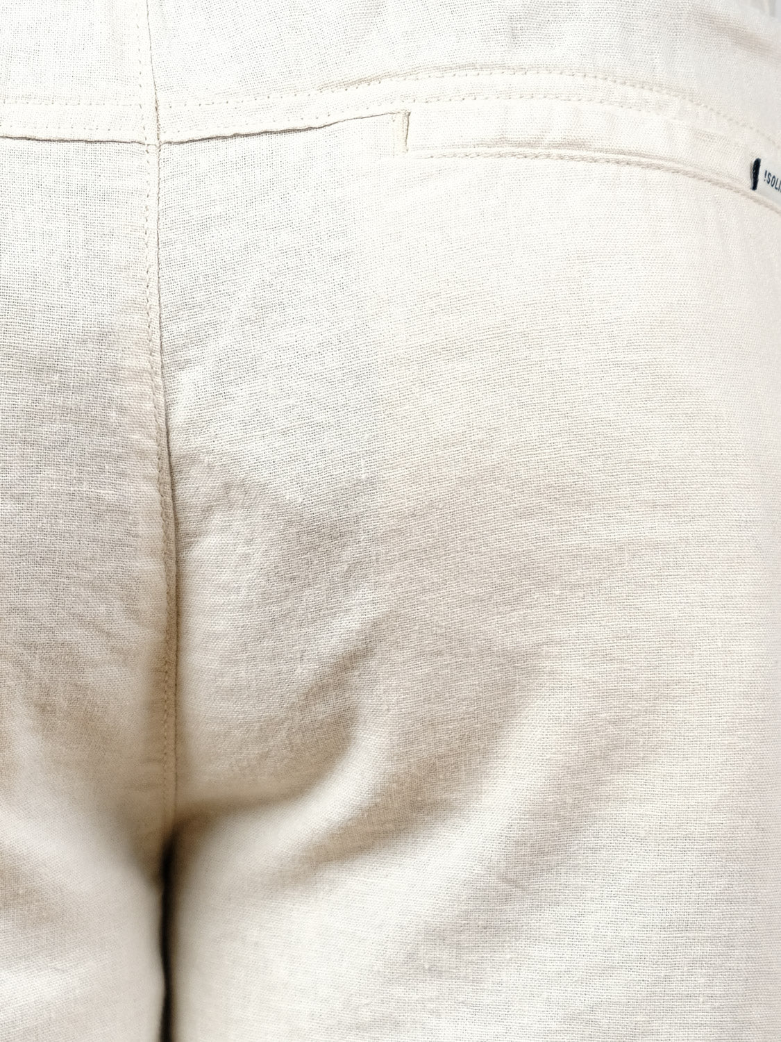 Close-up view of the back of the Aurelius Elas Short by !Solid in light beige, highlighting the seam, waistband, and part of a back pocket with a small label.
