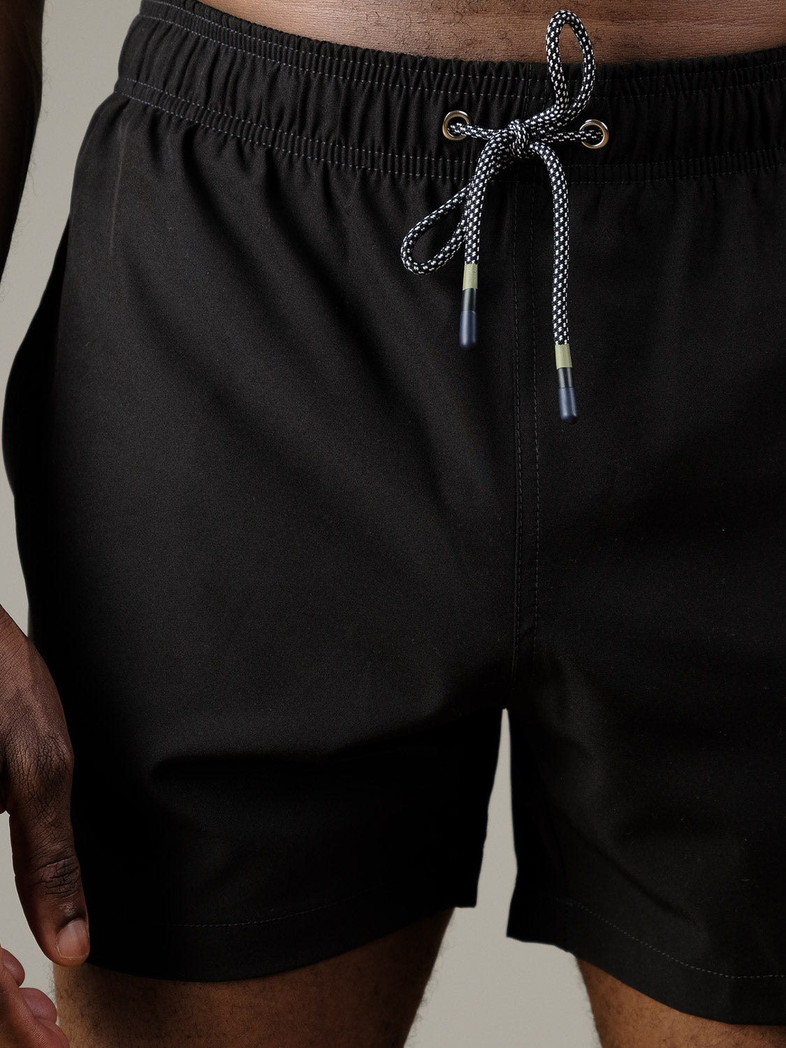 A person is shown from the waist down wearing ID Menswear’s Oyogu Quick Dry 4 Way Stretch Swim Trunk in black, featuring a white and black drawstring, against a neutral background.