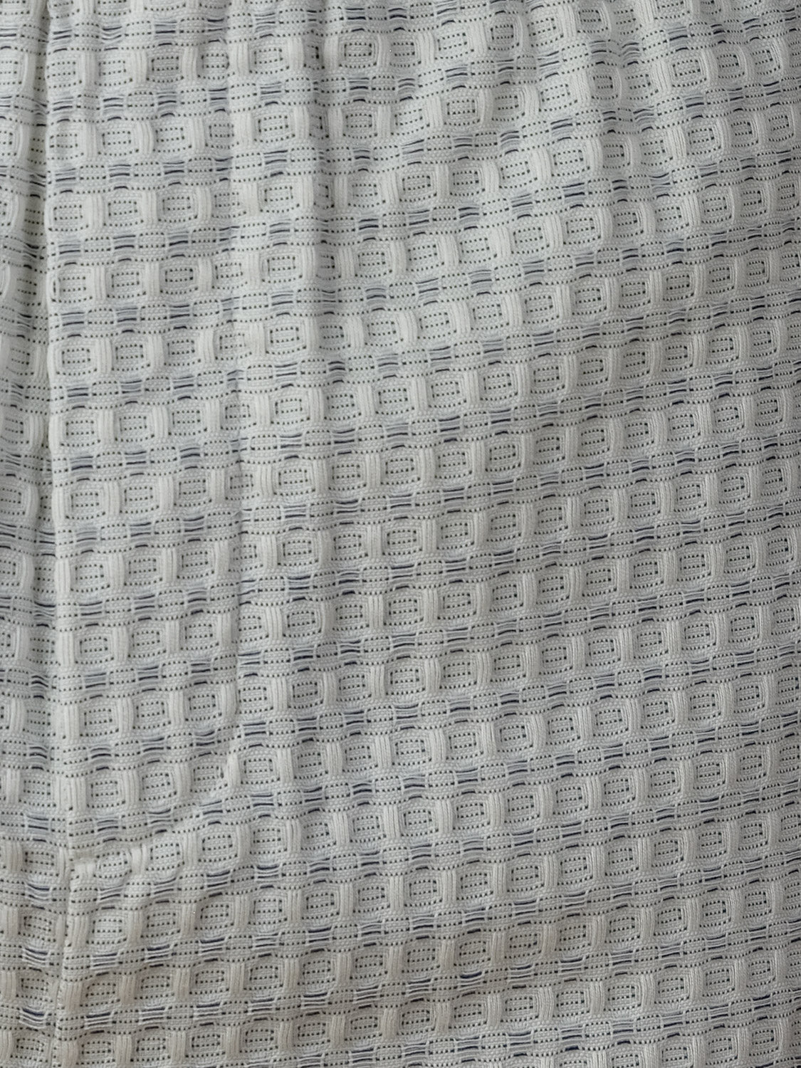 Close-up of the Check Seersucker Shorts by Les Deux, showing light gray textured fabric with a grid-like waffle pattern, visible seams, and slight folds.