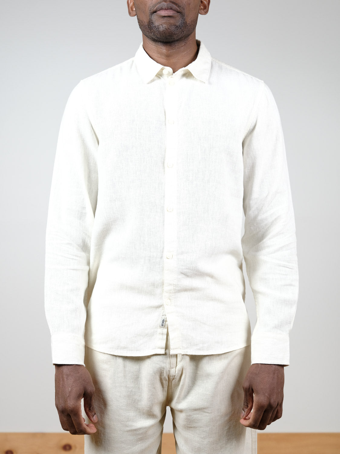 A person models the Enea Allan Long Sleeve Shirt by !Solid with matching white pants, standing against a plain background. Their face is partially out of frame, and their arms are relaxed at their sides.