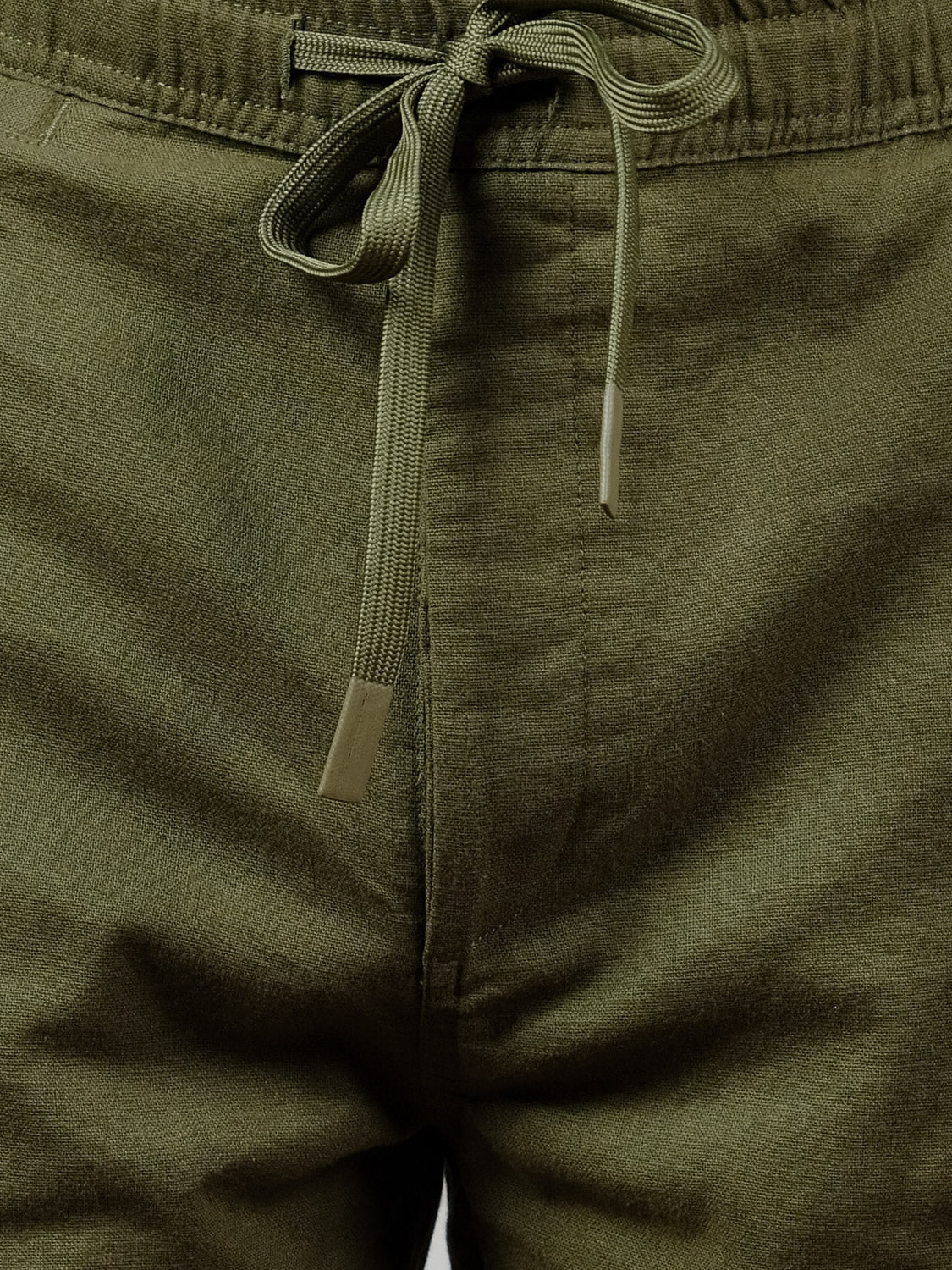 Close-up of the waistband and front of the olive green Laguna Linen Cotton Drawstring Pant by ID Menswear, featuring a drawstring with metal-tipped ends. The relaxed crop fit highlights its comfortable, easygoing linen-cotton style.