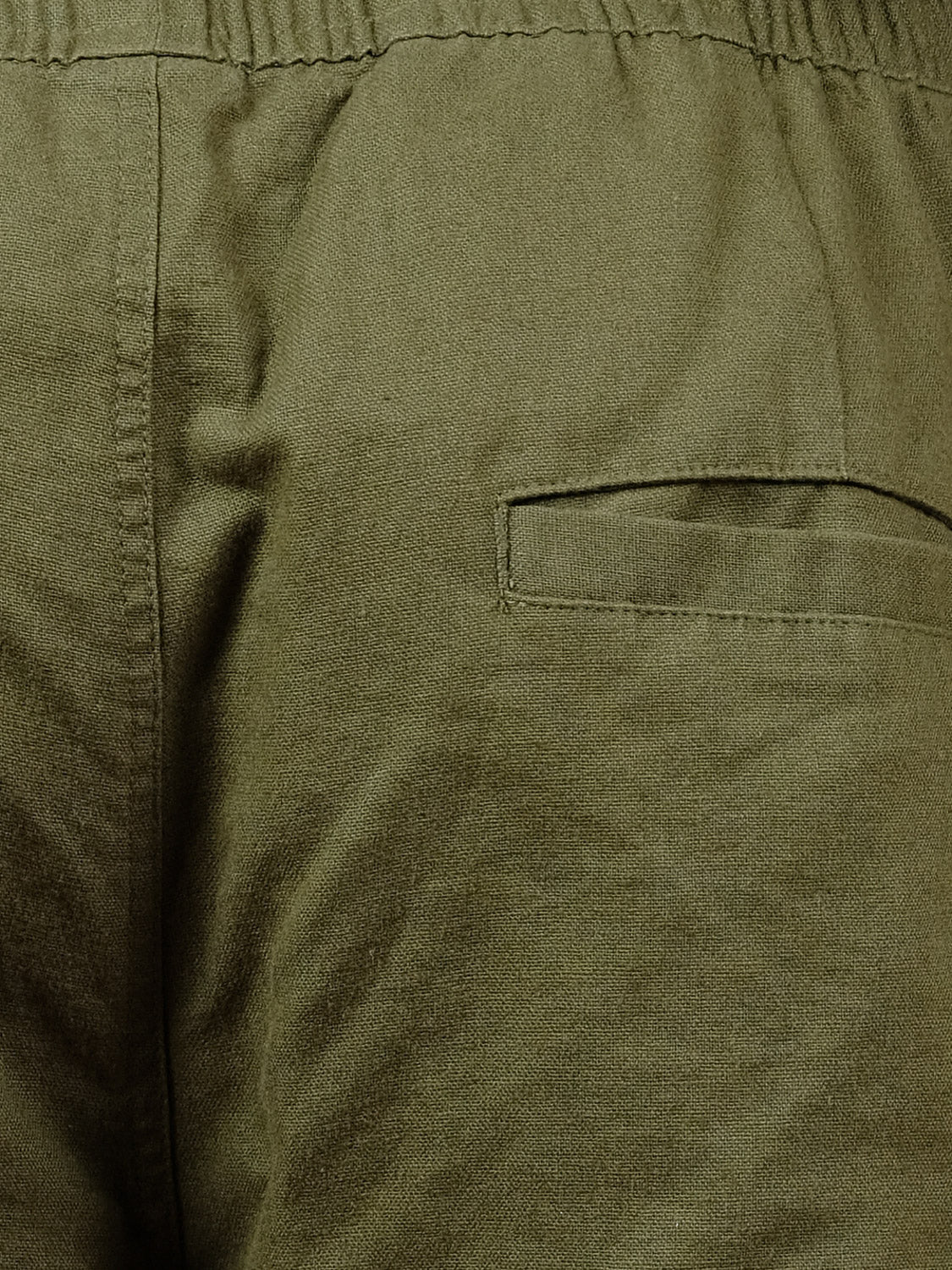 Close-up of the ID Menswear Laguna Linen Cotton Drawstring Pant in olive green, showcasing a relaxed cropped fit, adjustable drawstring waist, and a single flap back pocket.