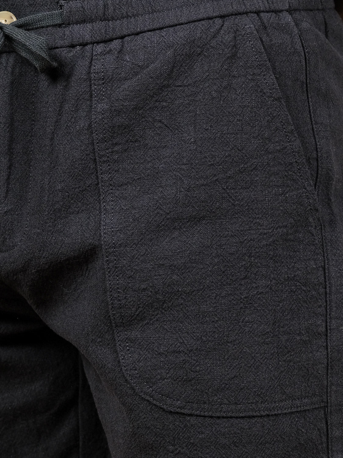 Close-up of the Phi Phi Linen Blend Drawstring Short by ID Menswear, showcasing textured fabric, a spacious front pocket, and an elastic waistband with drawstring for comfort.
