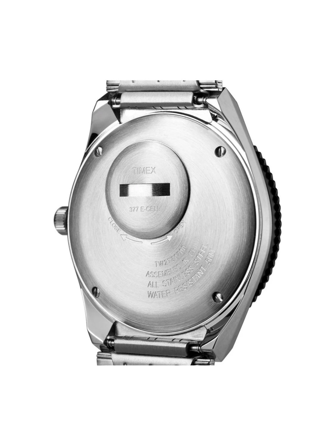 The image features the back of a Timex Q Timex Reissue 38mm Stainless Steel Bracelet Watch with engraved text, a black crown on the right, a battery compartment near the center, and part of the stainless steel bracelet visible.
