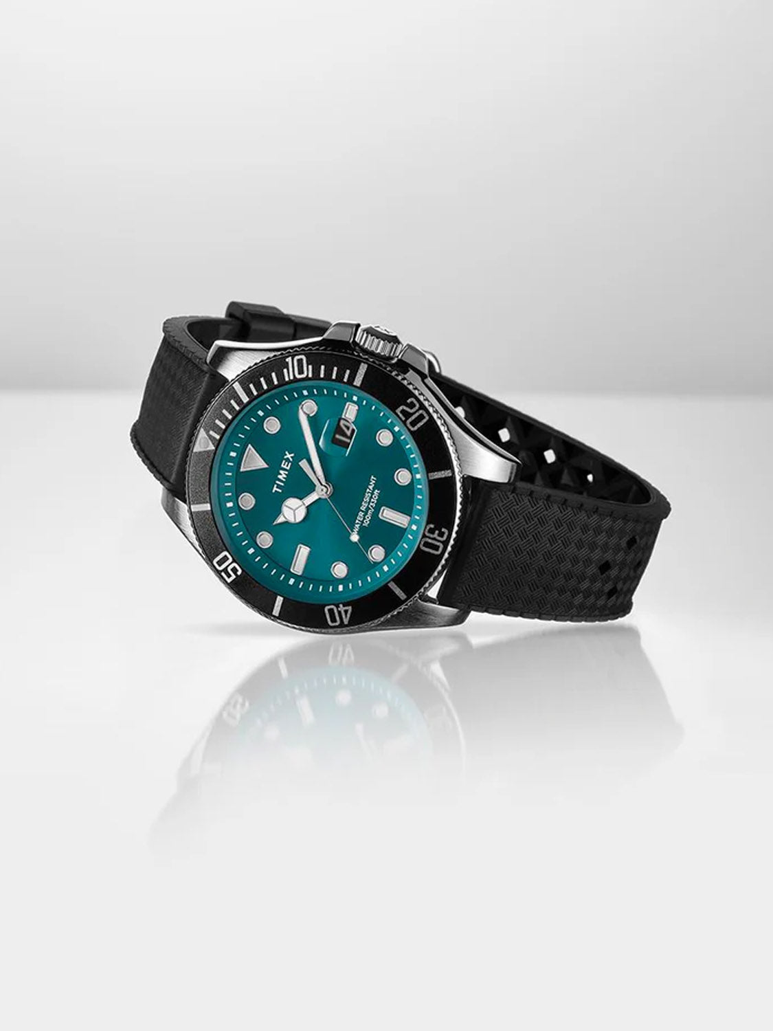 The Timex Harborside Coast 43mm Synthetic Rubber Strap Watch features an aventurine-colored dial, silver markers, black bezel, and textured strap. Resting angled on a white surface, it exudes stylish nautical appeal.