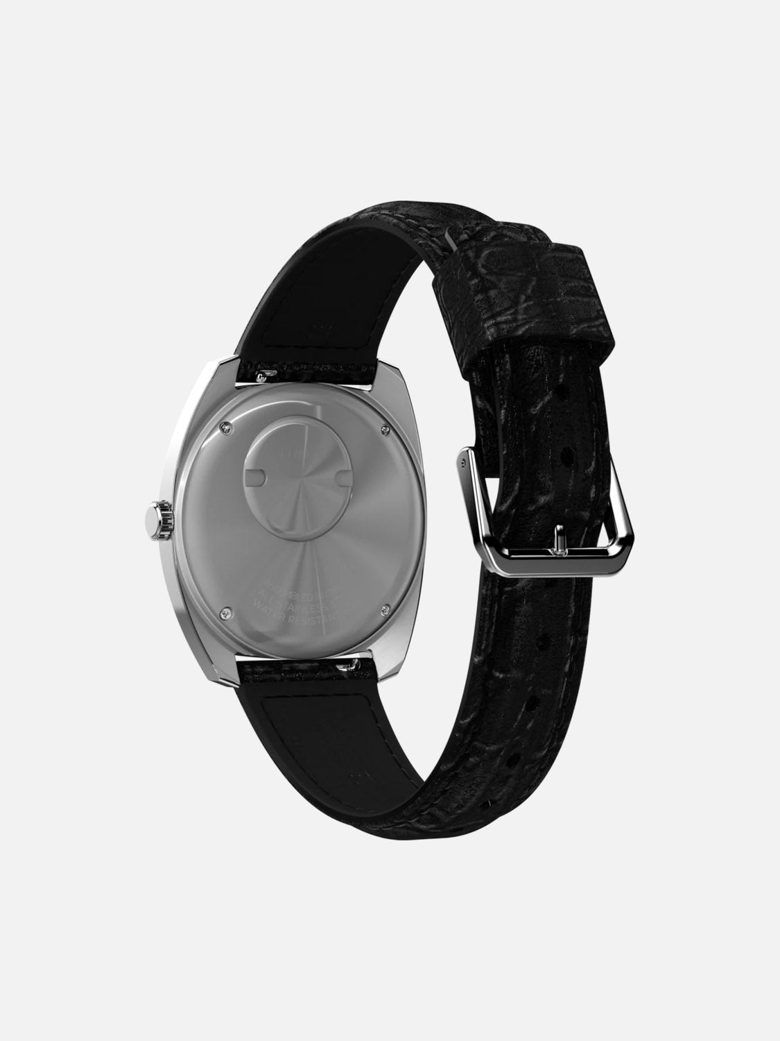 The Timex Q Timex 1978 Day/Date wristwatch in silver features a black textured leather strap, shown from the back to highlight its case and metal clasp, set against a plain white background.