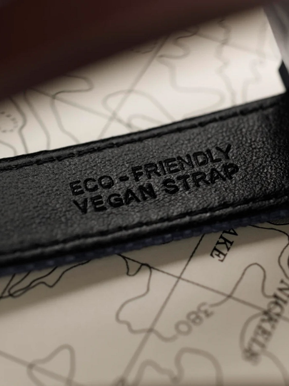 A detailed shot of the Timex Expedition Traprock Solar 40mms black Eco-Friendly Vegan Strap, stylishly matched with its eco-ceramic case. The strap is set against a map, highlighting lines and patterns that reflect its sustainable design by Timex.