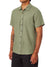 A person wears the Katin Alan Solid Shirt by Katin—a light green, short-sleeve button-up with a chest pocket—paired with black pants. A tattoo is visible on their left forearm. Face not visible.
