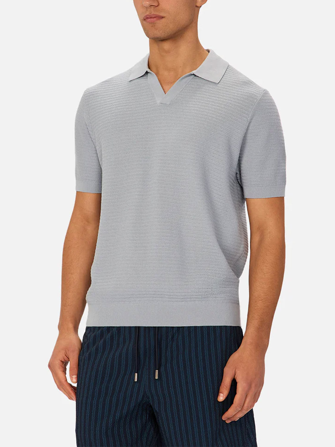 A person wearing Industrie’s The Alicante Polo in light gray, styled with dark blue pinstriped drawstring pants, stands against a plain white background.