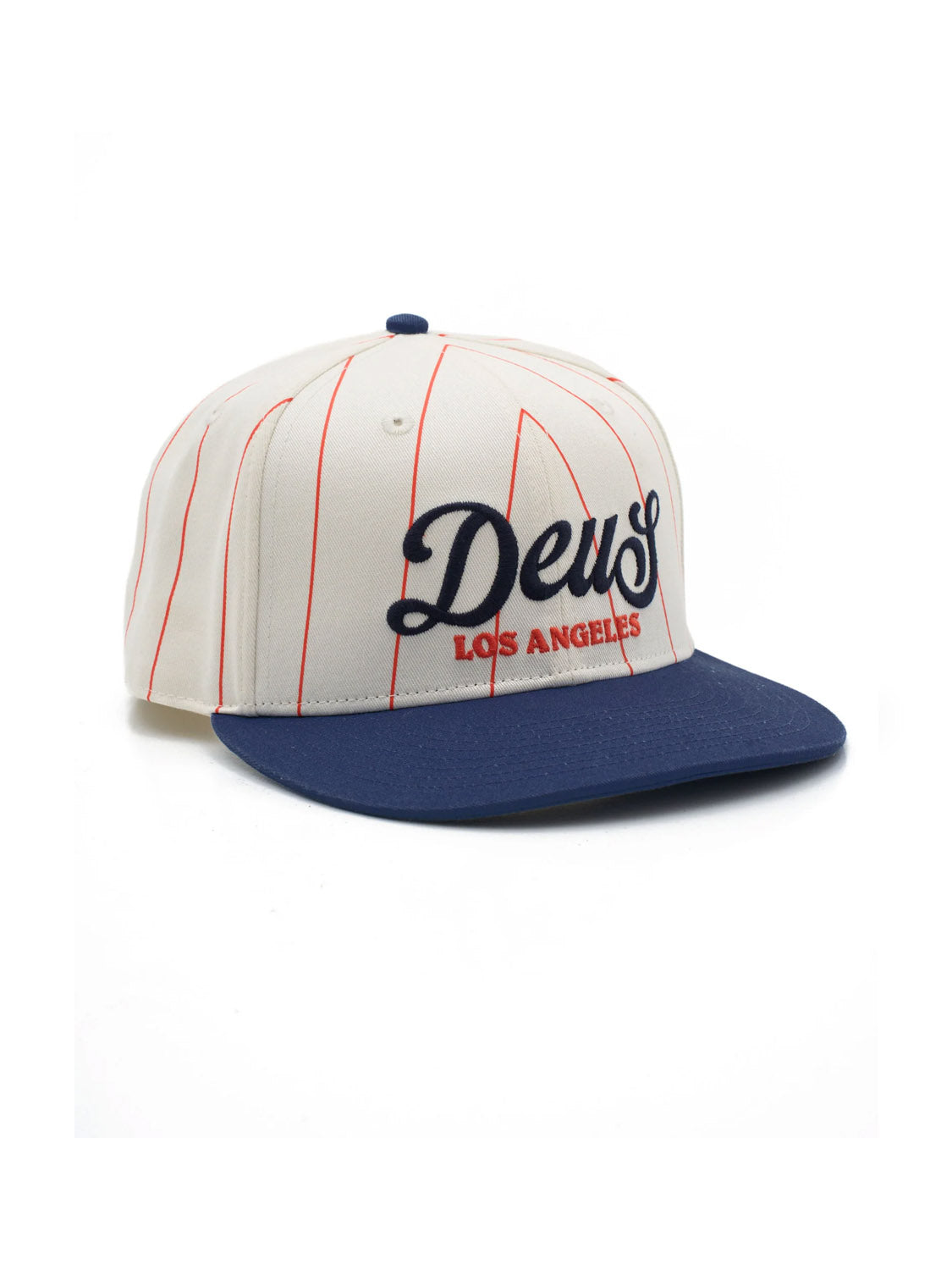 The Deus Alvia Cap is a vintage-inspired white cotton twill hat with thin red stripes, a navy brim, and “Deus Los Angeles” embroidered in navy and red. It features a snapback closure for adjustable fit.