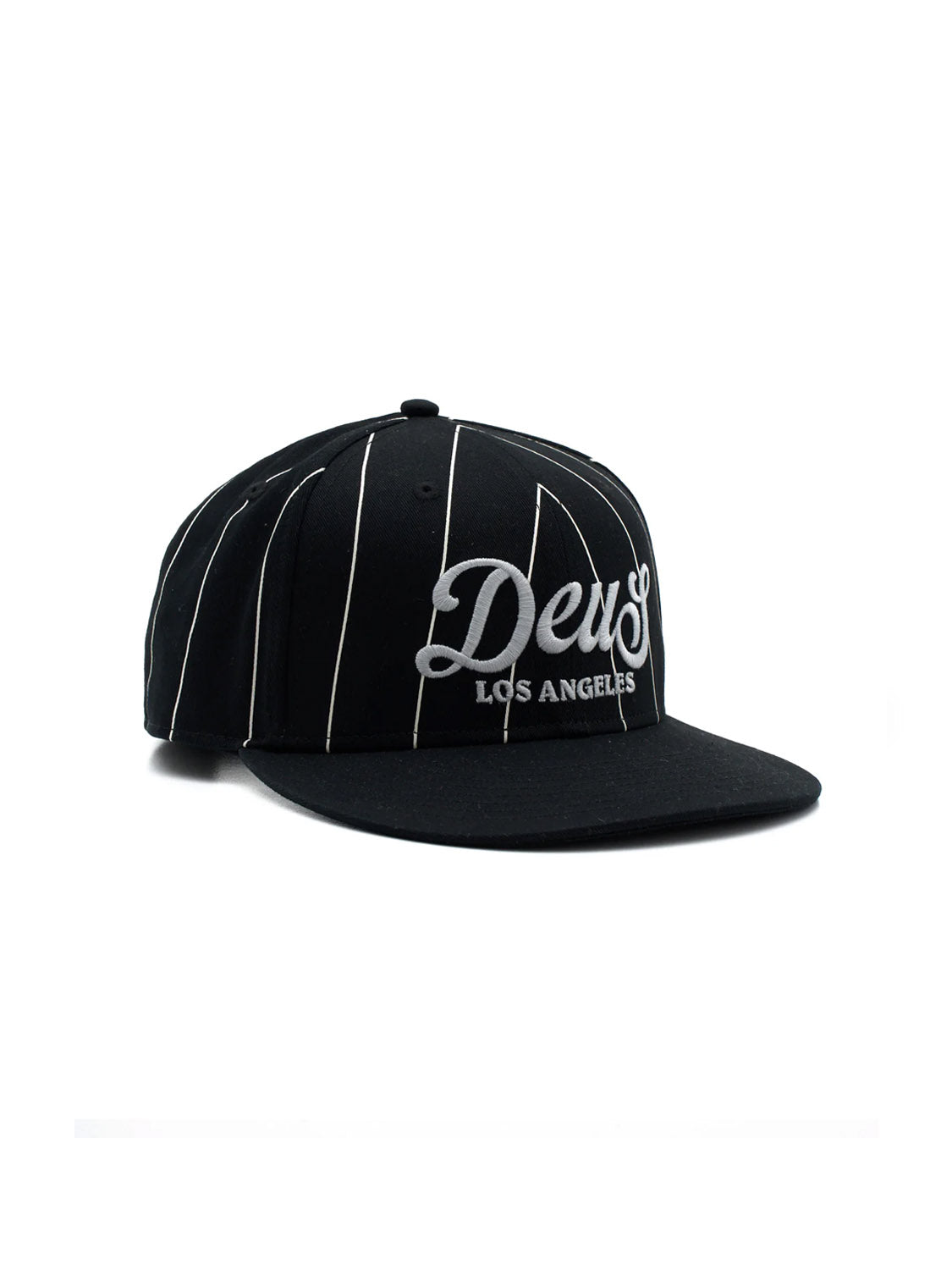 The Deus Alvia Cap is a black snapback with white pinstripes, made from cotton twill. It features "Deus" in large script and "Los Angeles" below, plus a flat brim and snapback closure for classic baseball hat style.