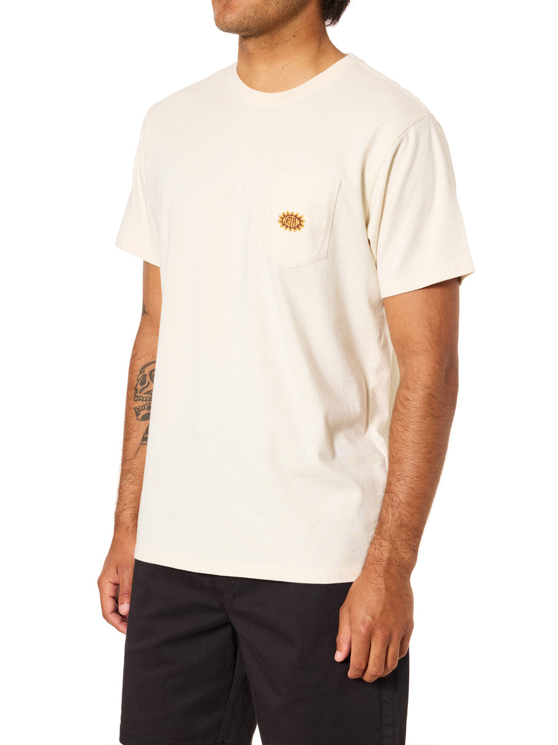 A person in a Katin Amoeba Pocket Tee—organic cotton, with a small embroidered sun on the chest pocket—by Katin, paired with black shorts, stands against a white background.