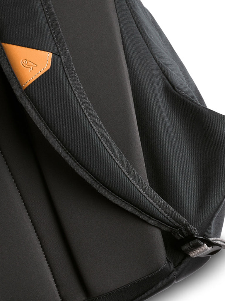 Close-up of the Bellroy Classic Backpack - 20L featuring a brown leather accent and small strap logo, showcasing its smooth, water-resistant fabric made from recycled materials and sturdy construction.
