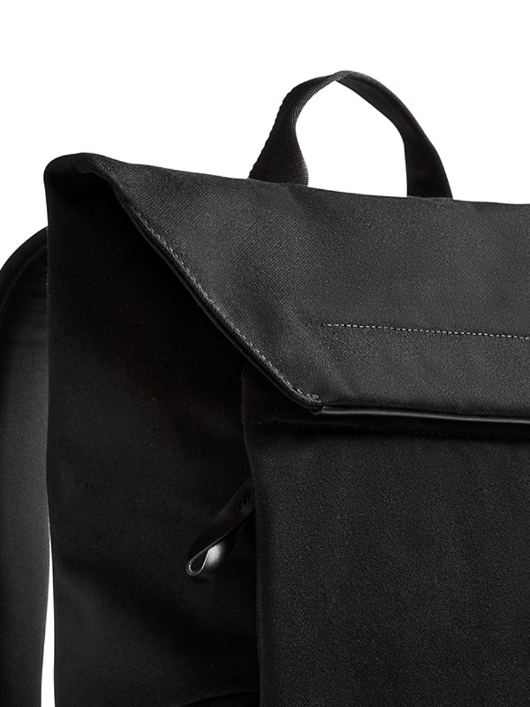 Close-up of the Bellroy Melbourne Backpack Compact - 13L in black, featuring a flap cover, front pocket, and top handle, set against a white background.