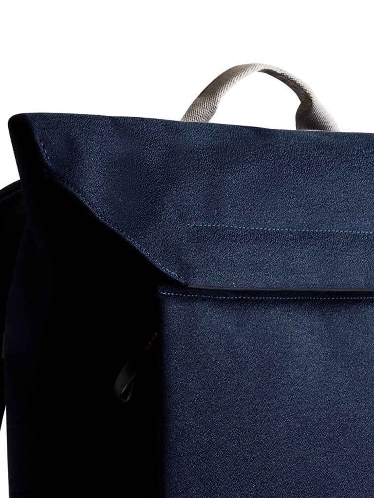 Close-up of the top portion of the Bellroy Melbourne Backpack - 18L in dark blue, showcasing a light gray handle, set against a white background.
