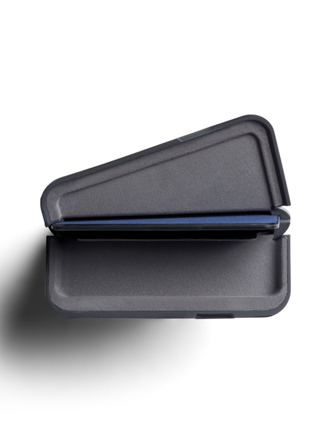 A top-down view of the Bellroy Flip Case Wallet, a closed, dark gray, triangular-shaped container with clean lines and a modern design, crafted from eco-tanned leather, resting on a white surface.