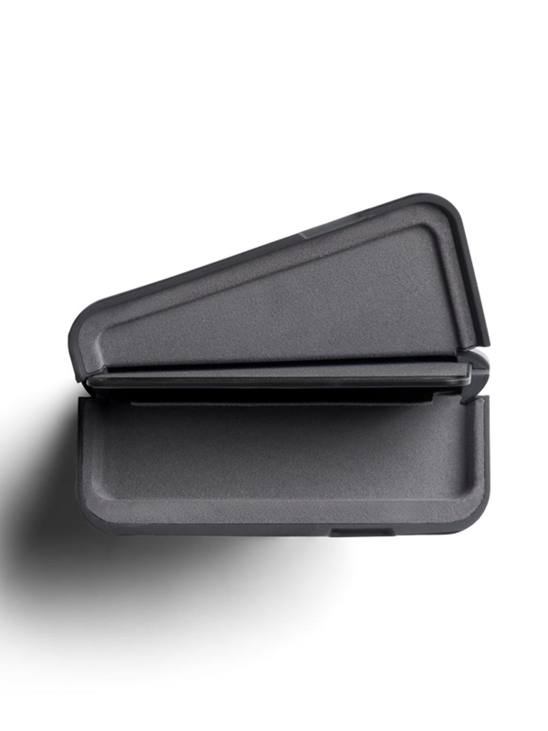 A top-down view of Bellroy’s Flip Case Wallet—a dark gray, triangular, clamshell-style container made from eco-tanned leather—slightly open and casting a shadow on a white background.