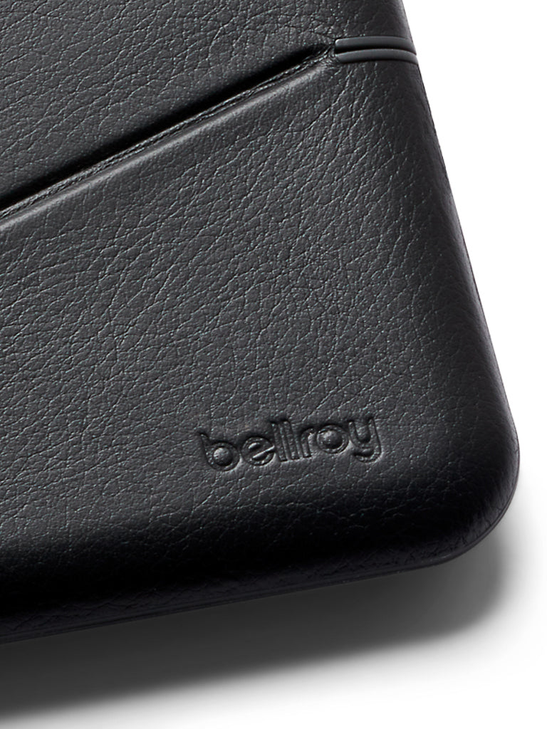 Close-up of the Bellroy Flip Case Wallet in black eco-tanned leather, featuring a subtle diagonal slot and the brand name embossed near the bottom right corner.
