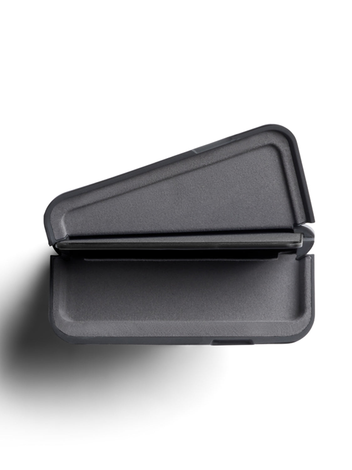 A top-down view of the Bellroy Flip Case Wallet: a closed, dark gray rectangle with a geometric, wedge-shaped lid crafted from eco-tanned leather, casting a shadow on a white surface.