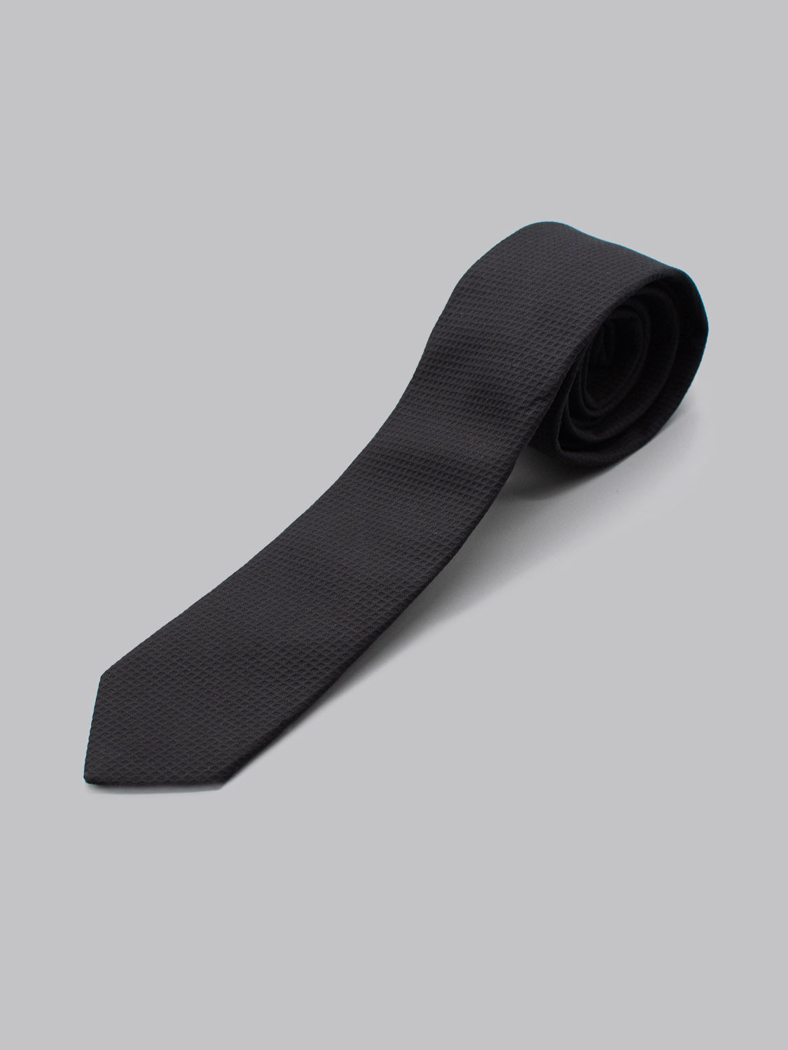 The ID Cotton Tie Berlin by ID Menswear is a black textured cotton tie, handmade in Brooklyn and rolled at one end, shown on a plain light grey background—ideal for business formal occasions.