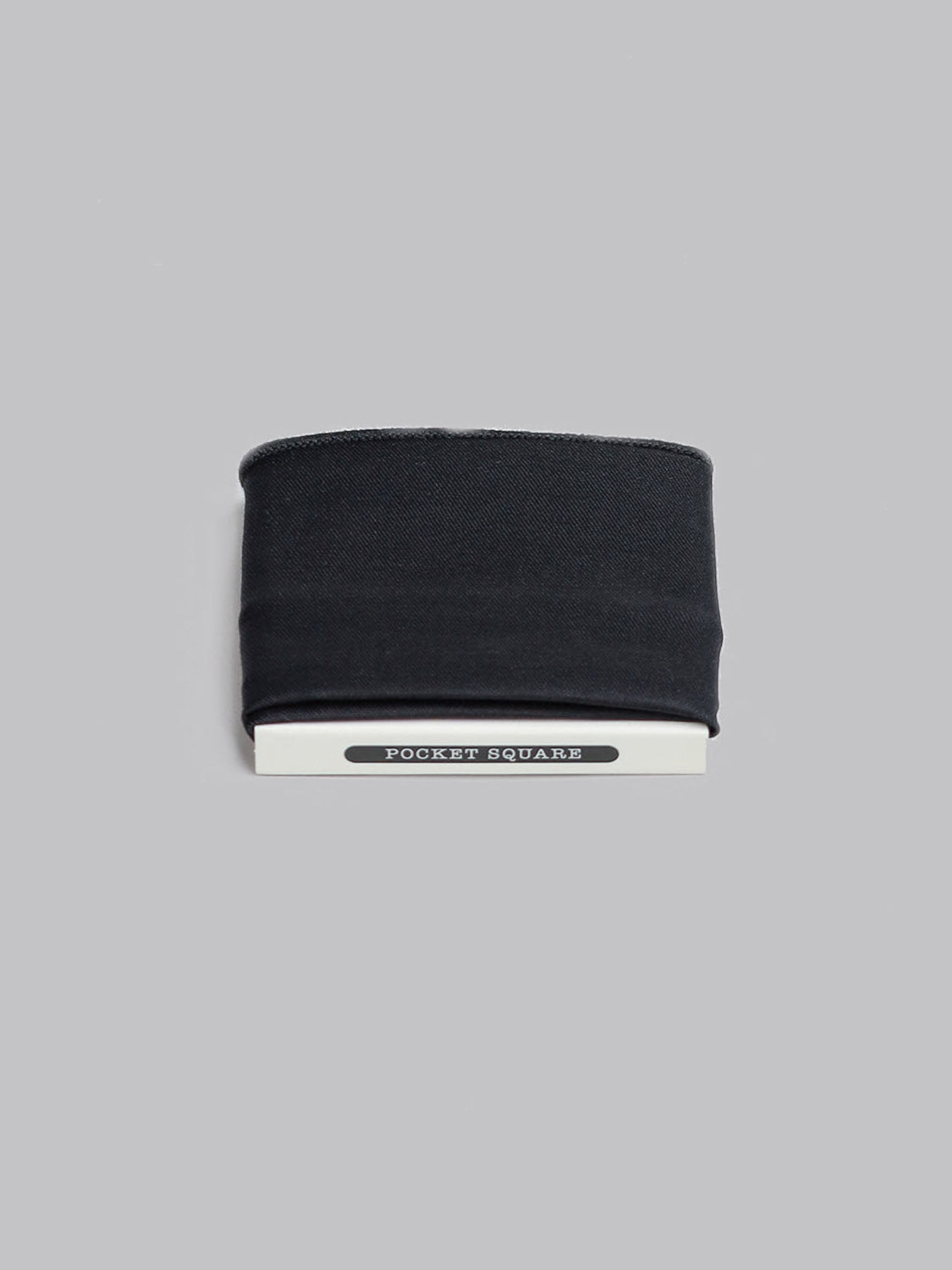 A Black Pocket Square by ID Menswear, made of 100% cotton, is neatly folded and displayed on a light gray background. It is partially held in a white card labeled Pocket Square.