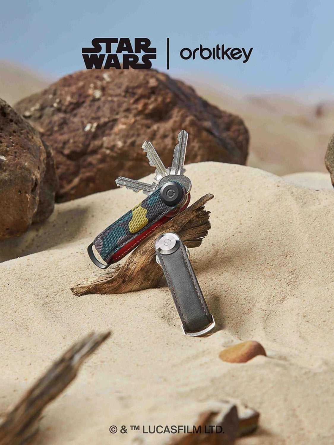 The Orbitkeys Star Wars Boba Fett Key Organizer is pictured on sand and driftwood with keys attached, rocks behind it, and Star Wars and Orbitkeys logos displayed at the top.