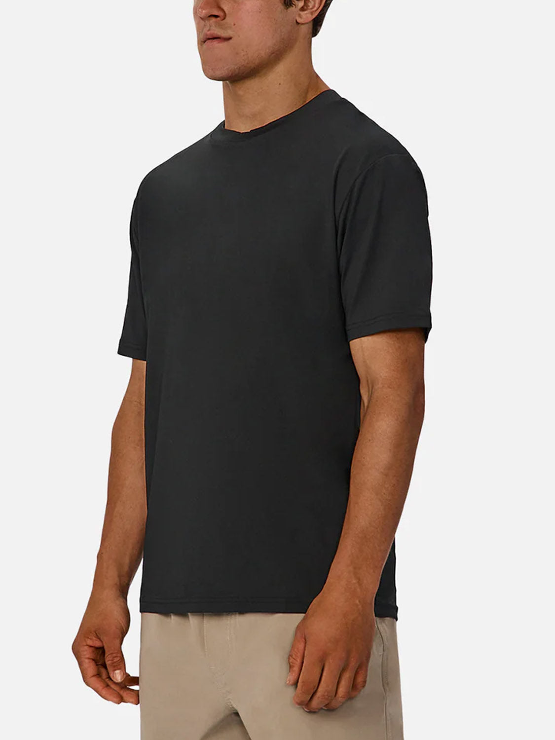A person models the Industrie Boldon T-Shirt, a plain black lightweight athletic top, with beige pants against a white background. Their head is partly out of frame and their arms rest relaxed at their sides.