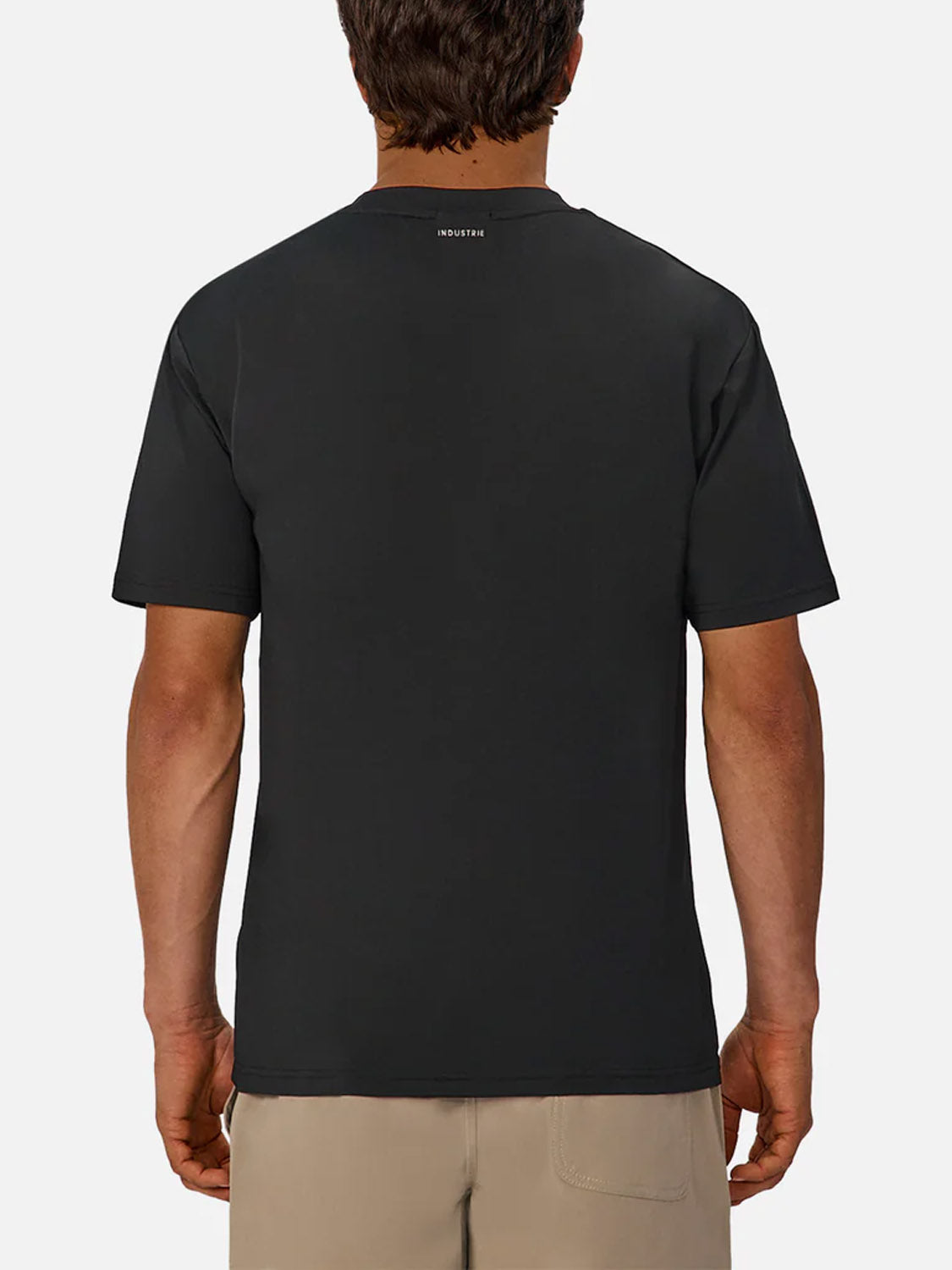 A man is seen from behind against a white background, wearing the Industrie Boldon T-Shirt in black with short sleeves, beige shorts, and a small white logo near the back neckline.